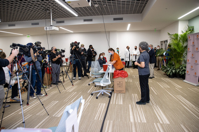 UT Health San Antonio officials prepare to administer the first COVID-19 vaccine surrounded by media and an assortment of cheering friends and colleagues.